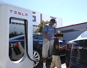FREMONT, CA – AUGUST 16:  Jinyao Desandies (R) and Dandre Desandies (L) plug the Tesla Supercharger into their Tesla Model S sedan outside of the Tesla Factory on August 16, 2013 in Fremont, California. Tesla Motors opened a new Supercharger station with four stalls for public use at their factory in Fremont, California. The Superchargers allow owners of the Tesla Model S to charge their vehicles in 20 to 30 minutes for free. There are now 18 charging stations in the U.S. with plans to open more in the near future.