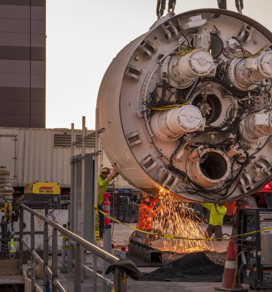 Workers cut the storage rack from the base of the drill head as the Boring Company prepares to lower the drill head for the People Mover tunnel which will connect convention halls as part of the LVCCD Phase 2 construction in the Red Lot east of the south Hall at the Las Vegas Convention center on Monday, Oct. 28, 2019. (Mark Damon/Las Vegas News Bureau)