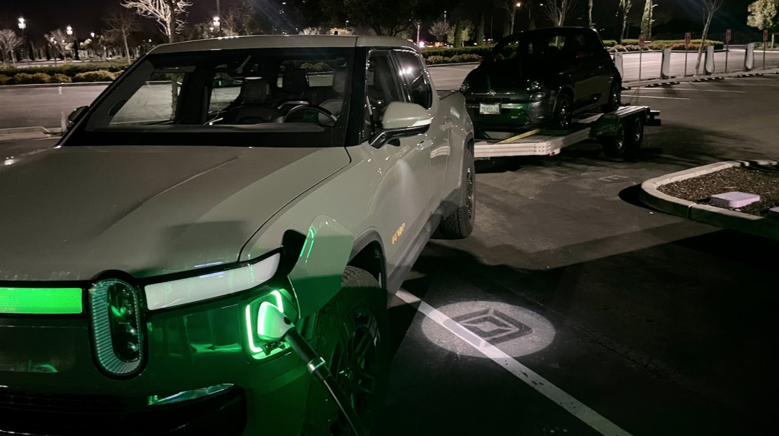 The Rivian R1T charging while towing the Fiat 500e