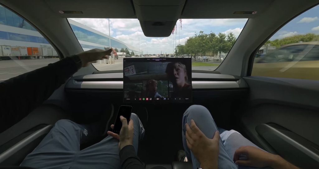 tesla cybercab with no manual controls showing a movie with two employees inside