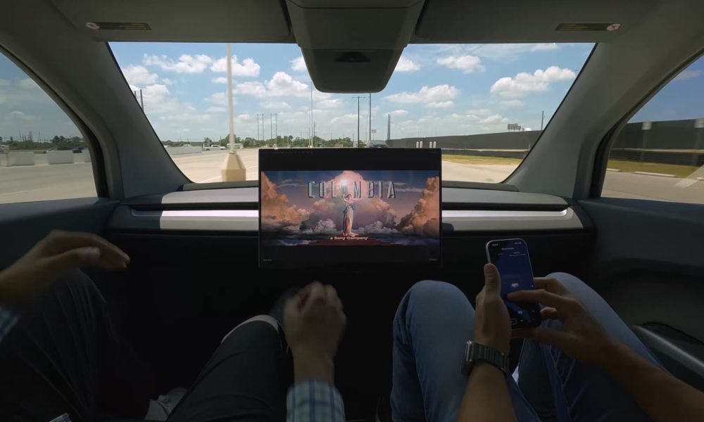 tesla cybercab with no manual controls showing a movie with two employees inside