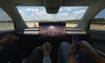tesla cybercab with no manual controls showing a movie with two employees inside