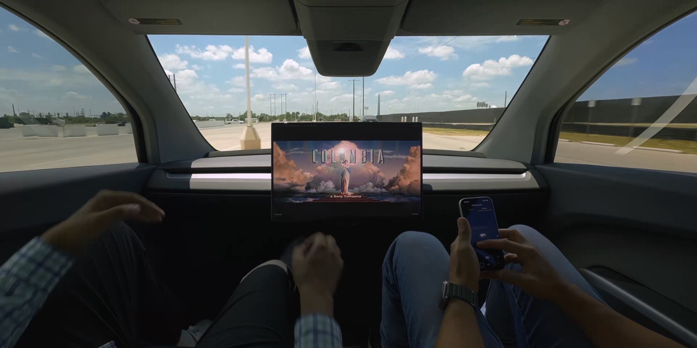 tesla cybercab with no manual controls showing a movie with two employees inside